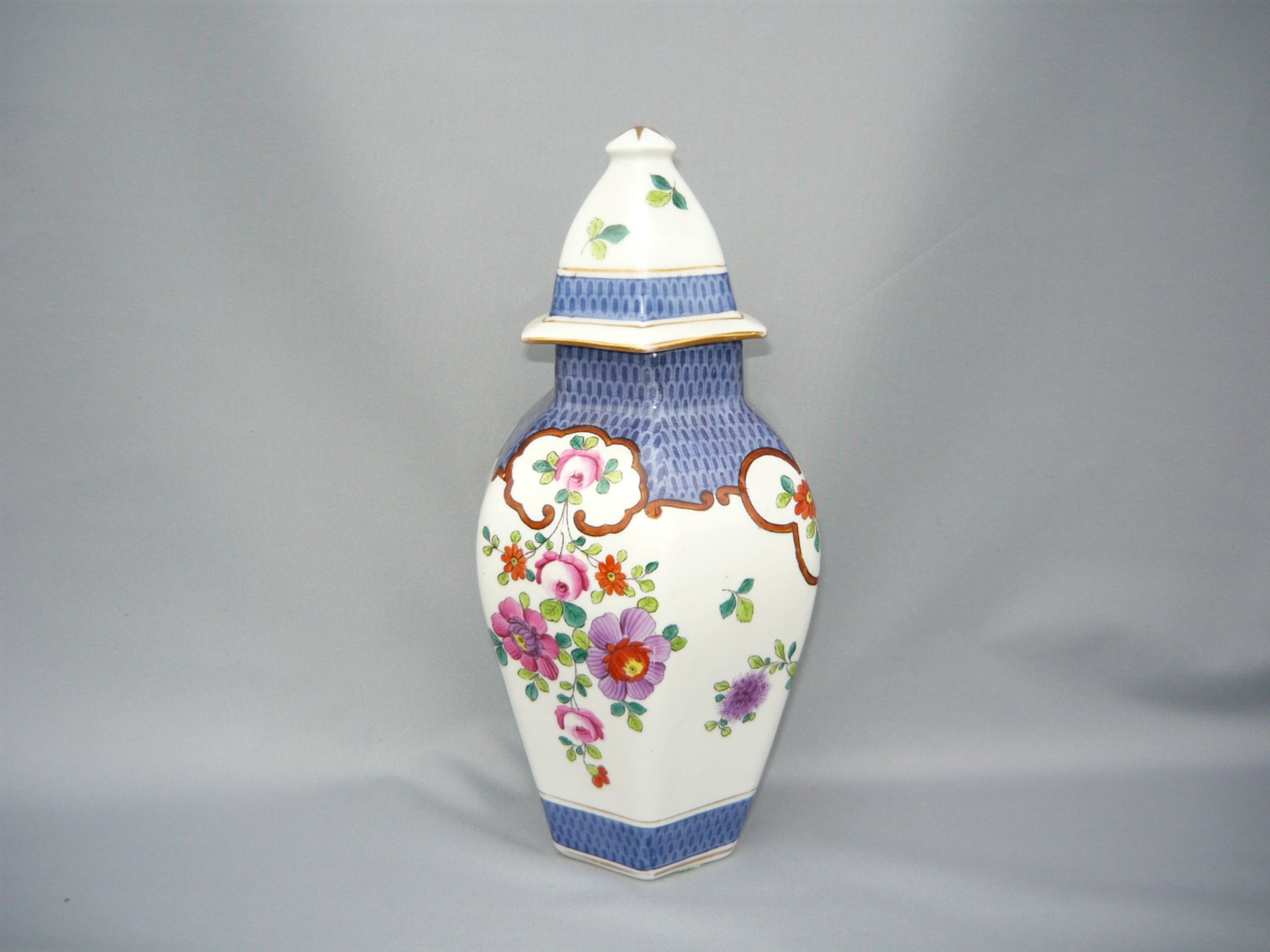 Hexagonale Deckelvase mit Handgemaltem Schuppen und Blumendekor. Unbek. Bodenmarke. H. 24cm.