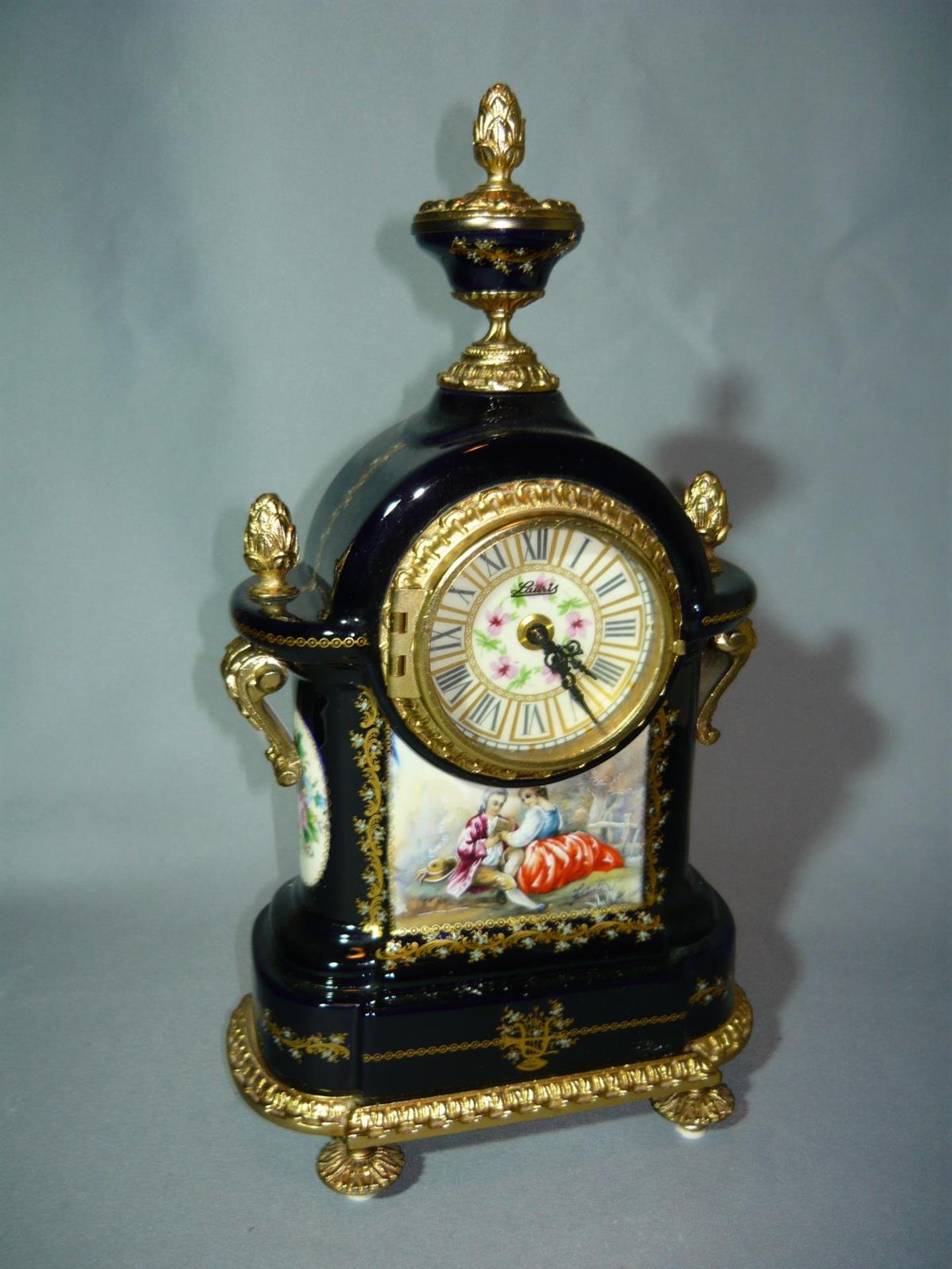 Prunkvolle Uhr mit galanter Szenerie. Um oder nach 1900. Rückseitig bezeichnet bleu Sevres. H. 34cm.