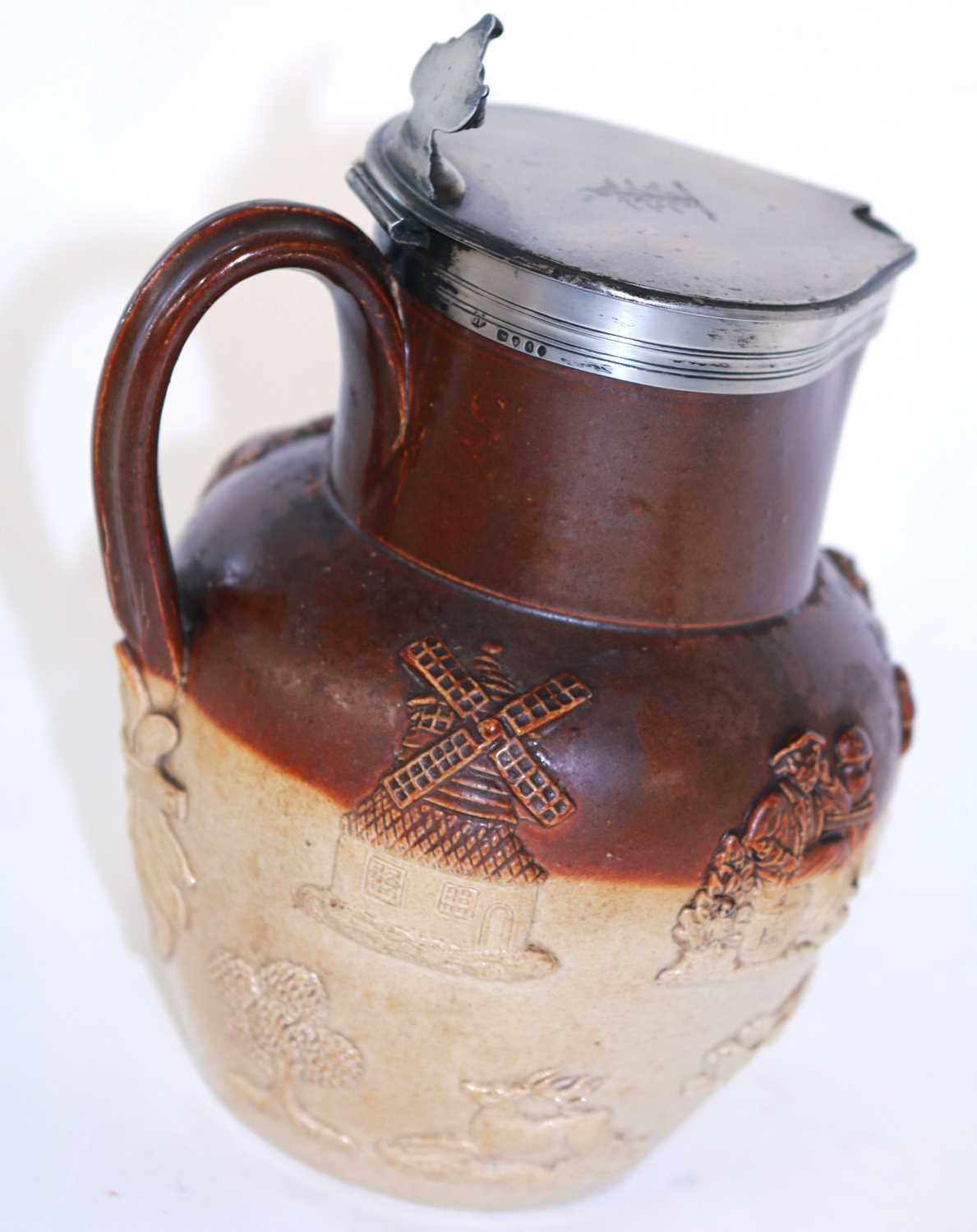 A salt glaze harvest jug with silver mounts and lid.