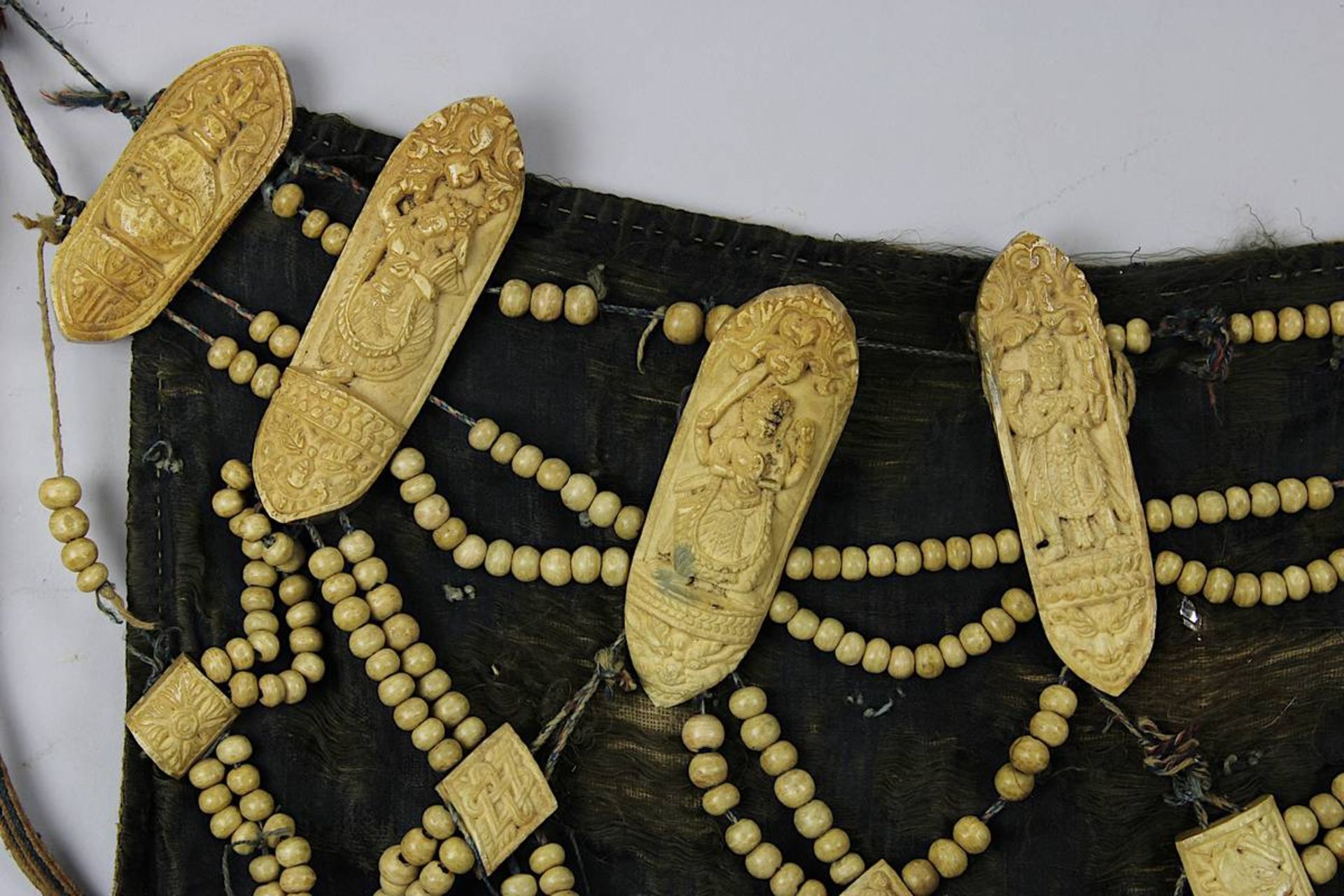 Knochenschürze, Tibet, wohl 19. Jh., dunkler Stoff, mit Netzwerk aus Knochenperlen u. Amuletten in - Bild 3 aus 5