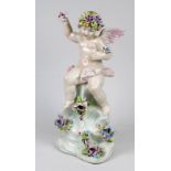 Auf Felsen mit Blüten sitzende Amorette, Porzellanfigur, Capodimonte Neapel, Ende 20. Jh., farbig