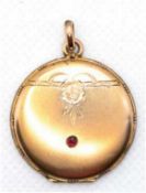 Medaillon um 1900, Golddouble, mit zeittypischem Dekor und rotem Schmuckstein, Durchmesser ca. 2,7 