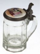 Bierkrug, 19. Jh., farbloses Glas und Zinndeckel, bemalte Deckelplakette mit figürlicher Darstellun
