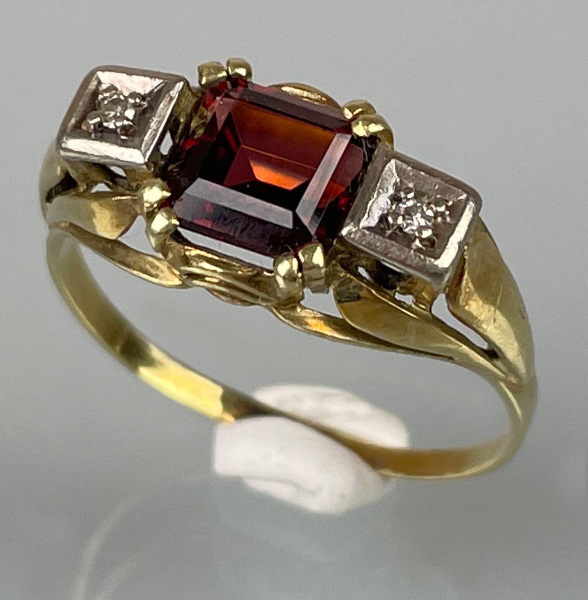Damenring 585 Gelbgold / Weißgold mit 2 kleinen Diamanten und einem roten Farbstein.