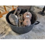 A quantity of timber and metal Pulleys in a cast iron cauldron..