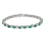 Riviere bracelet in 18kts white gold interspersed with emeralds, oval cut, and groups of four