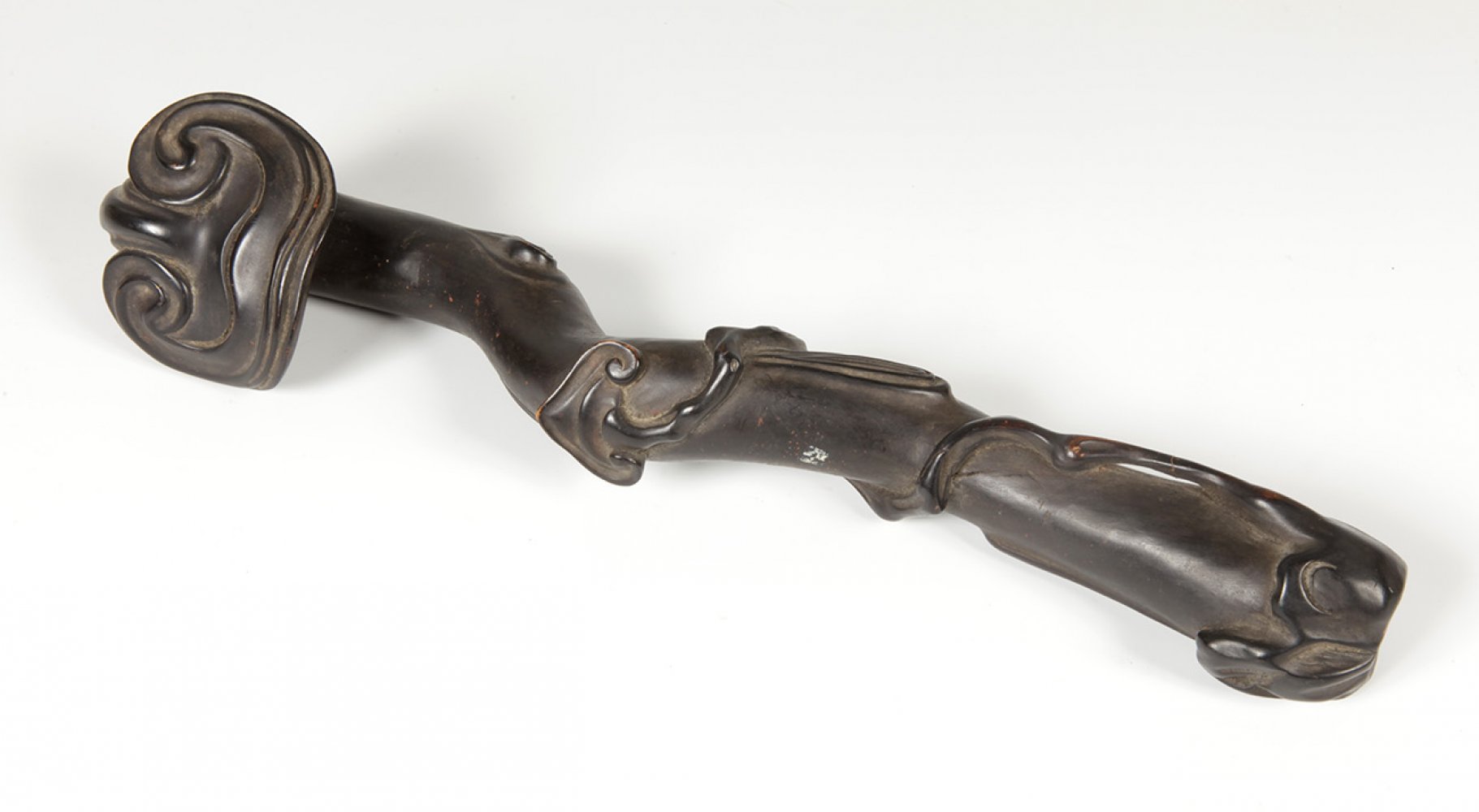 Ruyi sceptre; Liaoning, China, 19th century.Carved wood.Measurements: 37 cm long.This type of