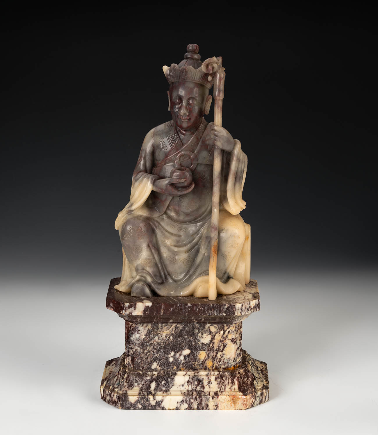 Luohan. China, XIX century.Hand carved soapstone on marble base.Measures: 20 x 10x 6 cm (figure);