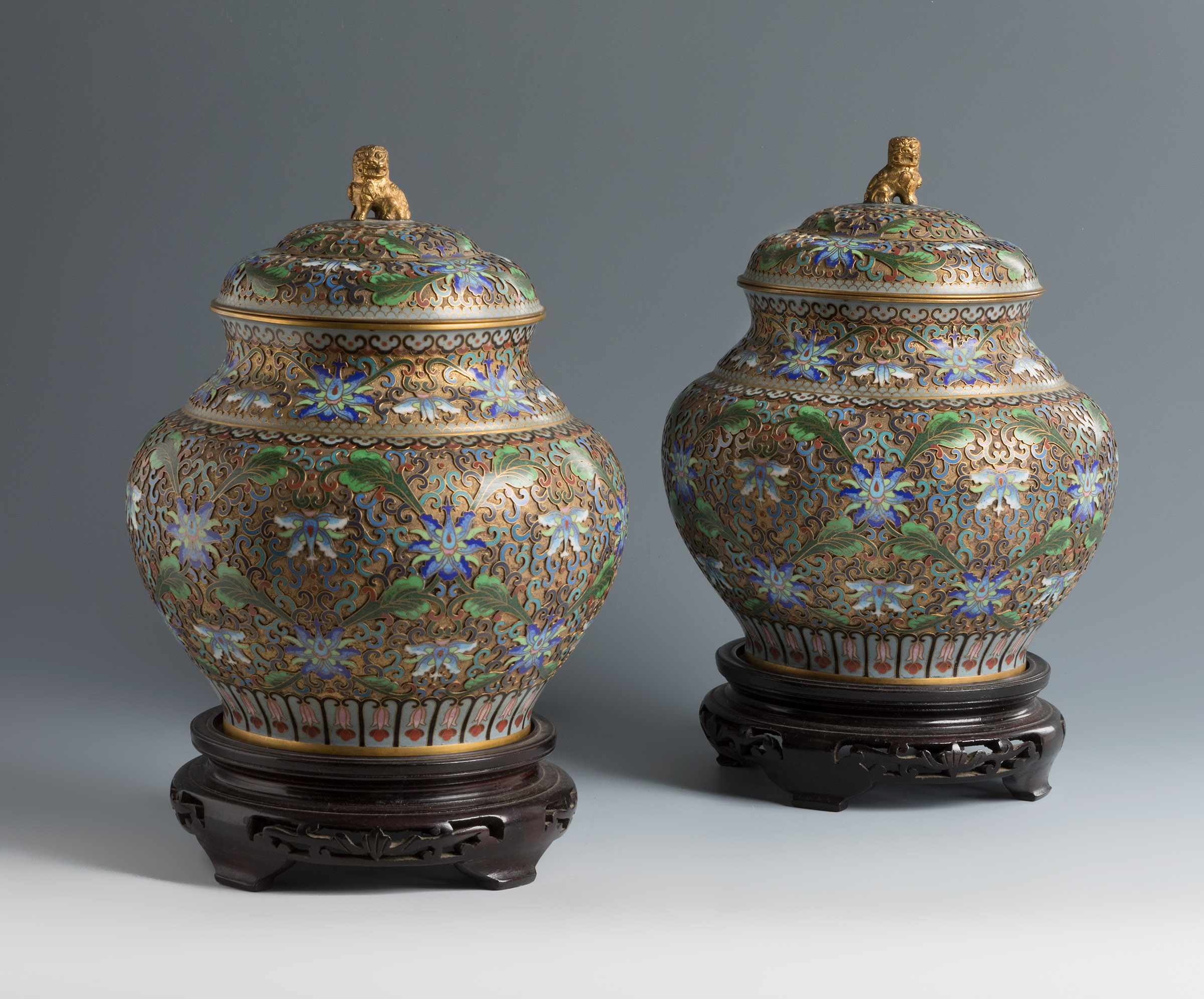 Pair of ginger storage jars. China, 1920-1940.Bronze and cloisonné enamel. Carved wooden bases.