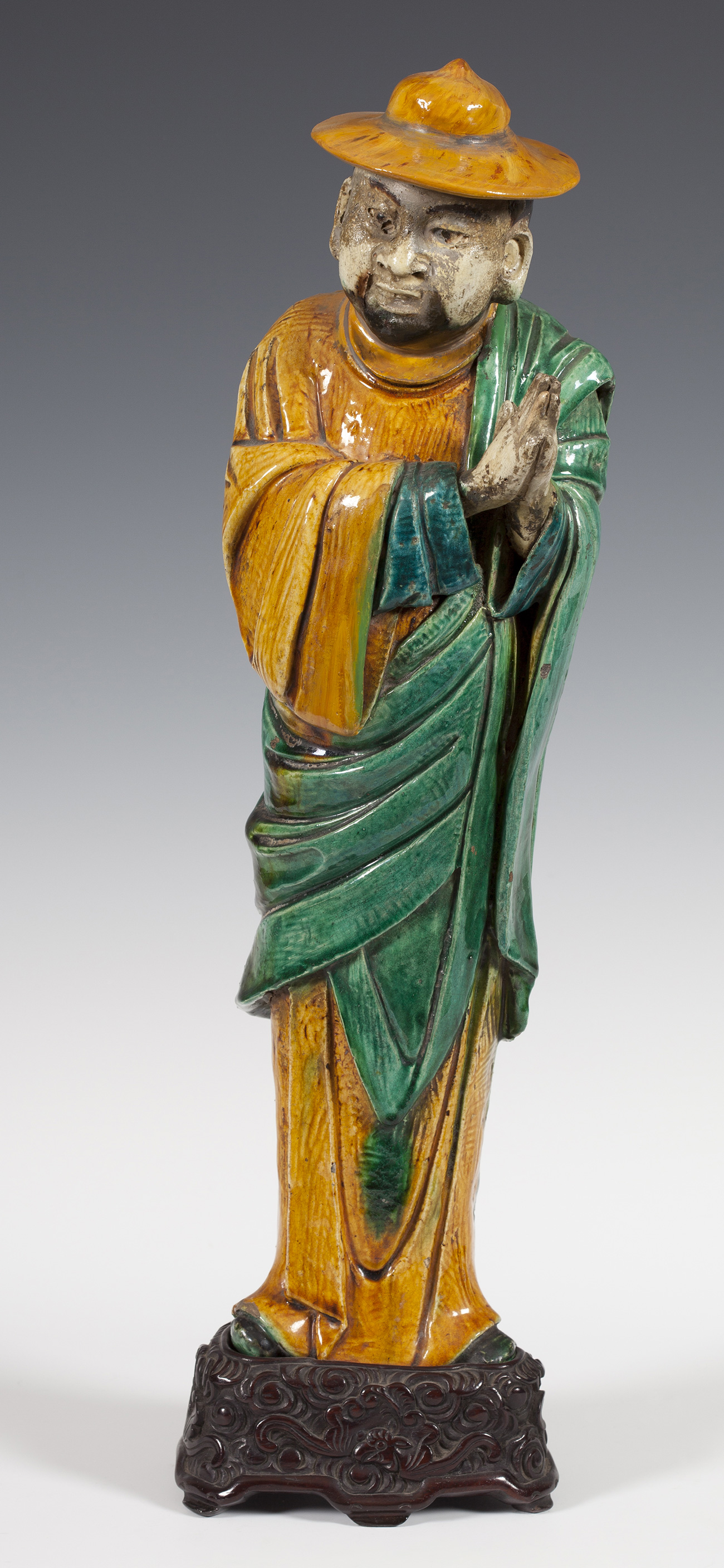 Figure of a monk. China, early 19th century.Stoneware and carved wooden base.Measurements: 51 x 14 x