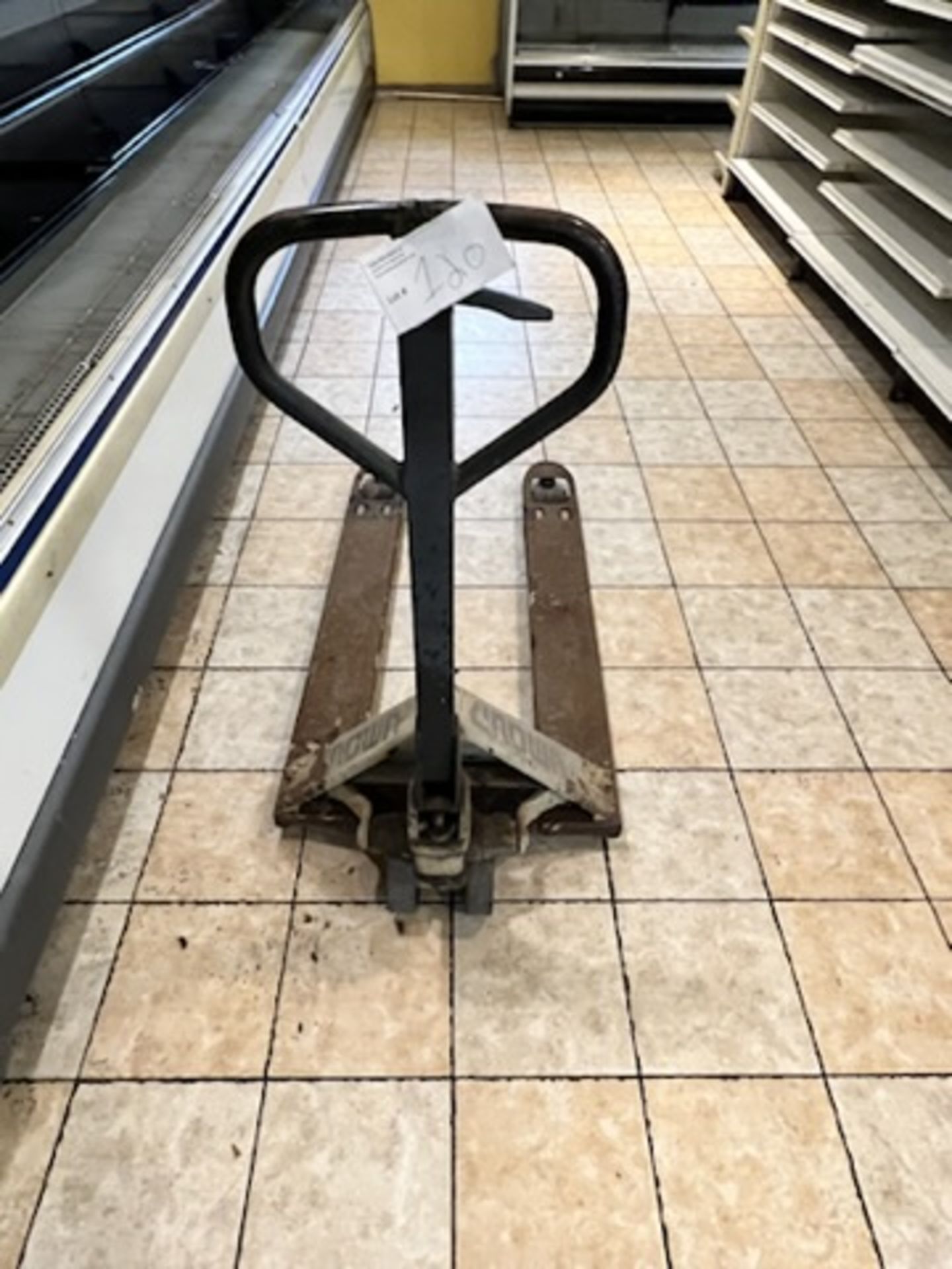 Crown Manual Pallet Jack, operational w/ signs of visible rust.
