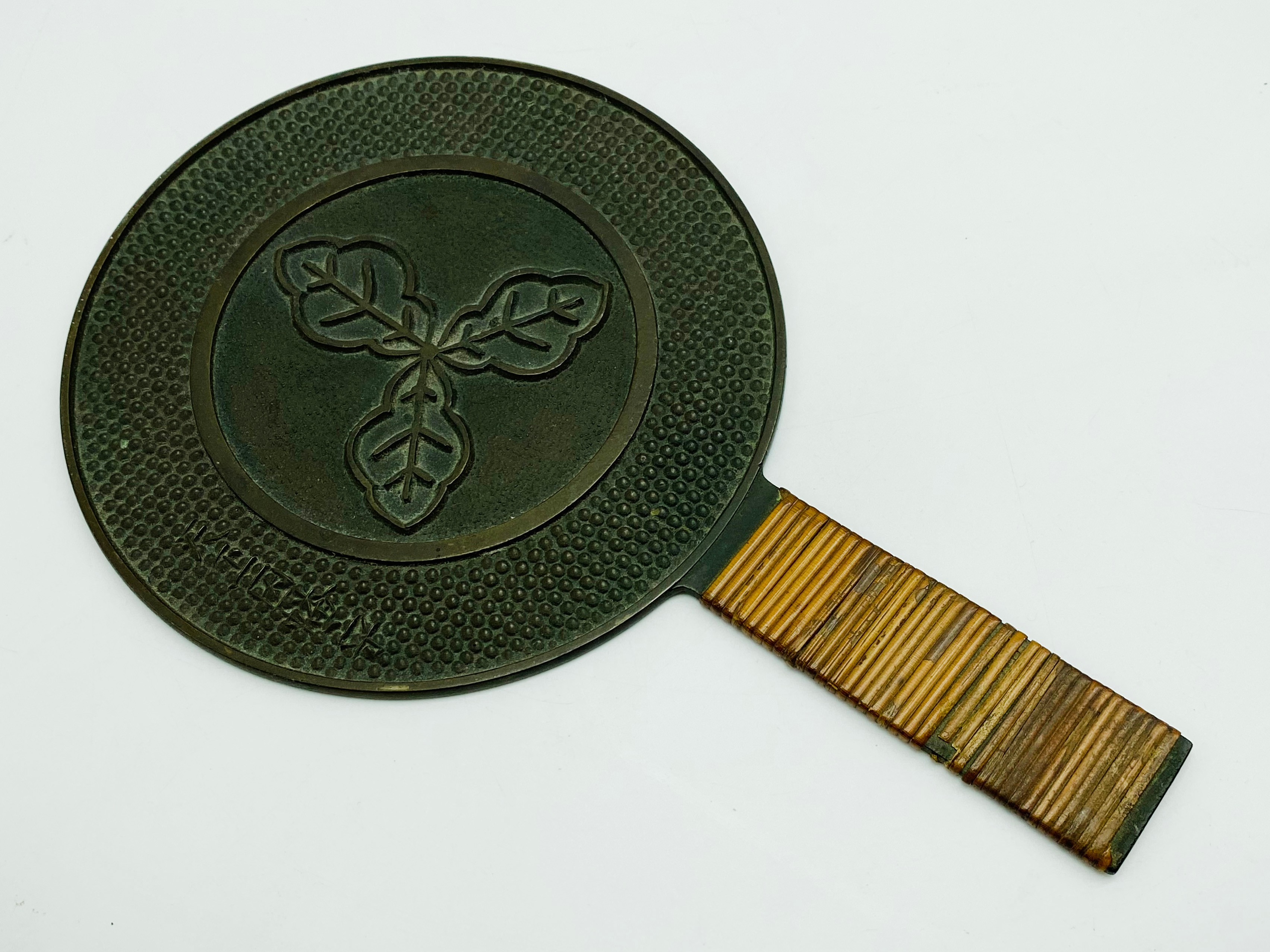 A 19TH-CENTURY JAPANESE BRONZE HAND MIRROR DECORATED TO THE REVERSE WITH A CLAN CREST (MON)