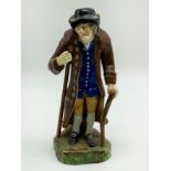 A STAFFORDSHIRE CERAMIC FIGURE OF AN ELDERLY MAN DEPICTING "AGE" WEARING A BROWN GLAZED COAT