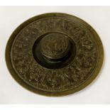 LARGE DISC-SHAPED ANTIQUE BRONZE INKWELL ENGRAVED THROUGHOUT WITH HORSEMAN AND WARRIORS