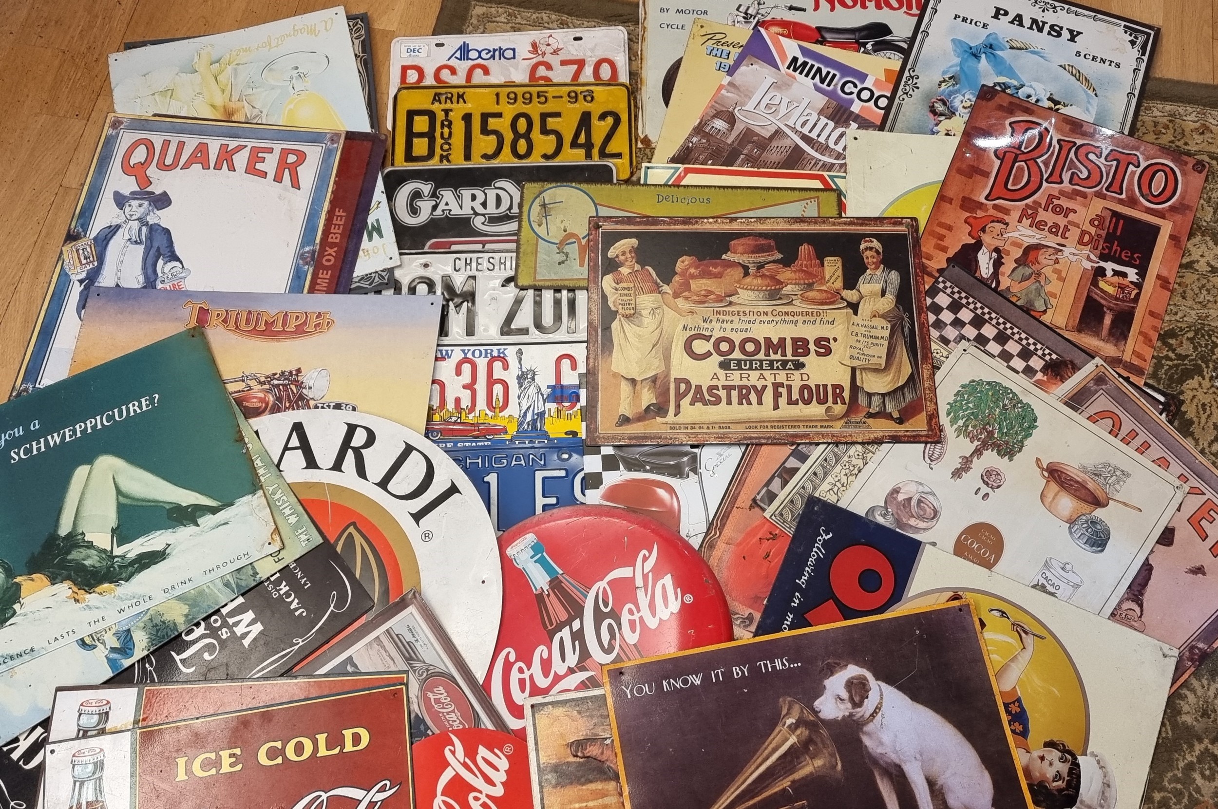 A large collection of printed tin advertising signs and USA number plates