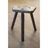 A 19th century fruitwood milking stool, shaped seat with tapering legs, 50cm x 22cm