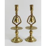 A pair of 19th century brass tavern type socket candlesticks with central column bell and circular