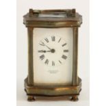 A French brass carriage clock, with serpentine shaped case, beveled edge glass panels and door,