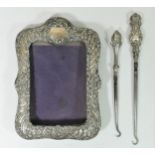 A silver embossed photograph frame, Birmingham 1906, 20 x 14cm and two silver button hooks (3)