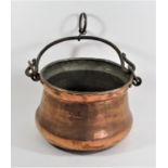 A hand beaten copper cauldron, of bulbous form with wrought iron swivel handle and tinned