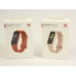 A pair of Huawei band 4 smart watches, in pink and red, original boxes