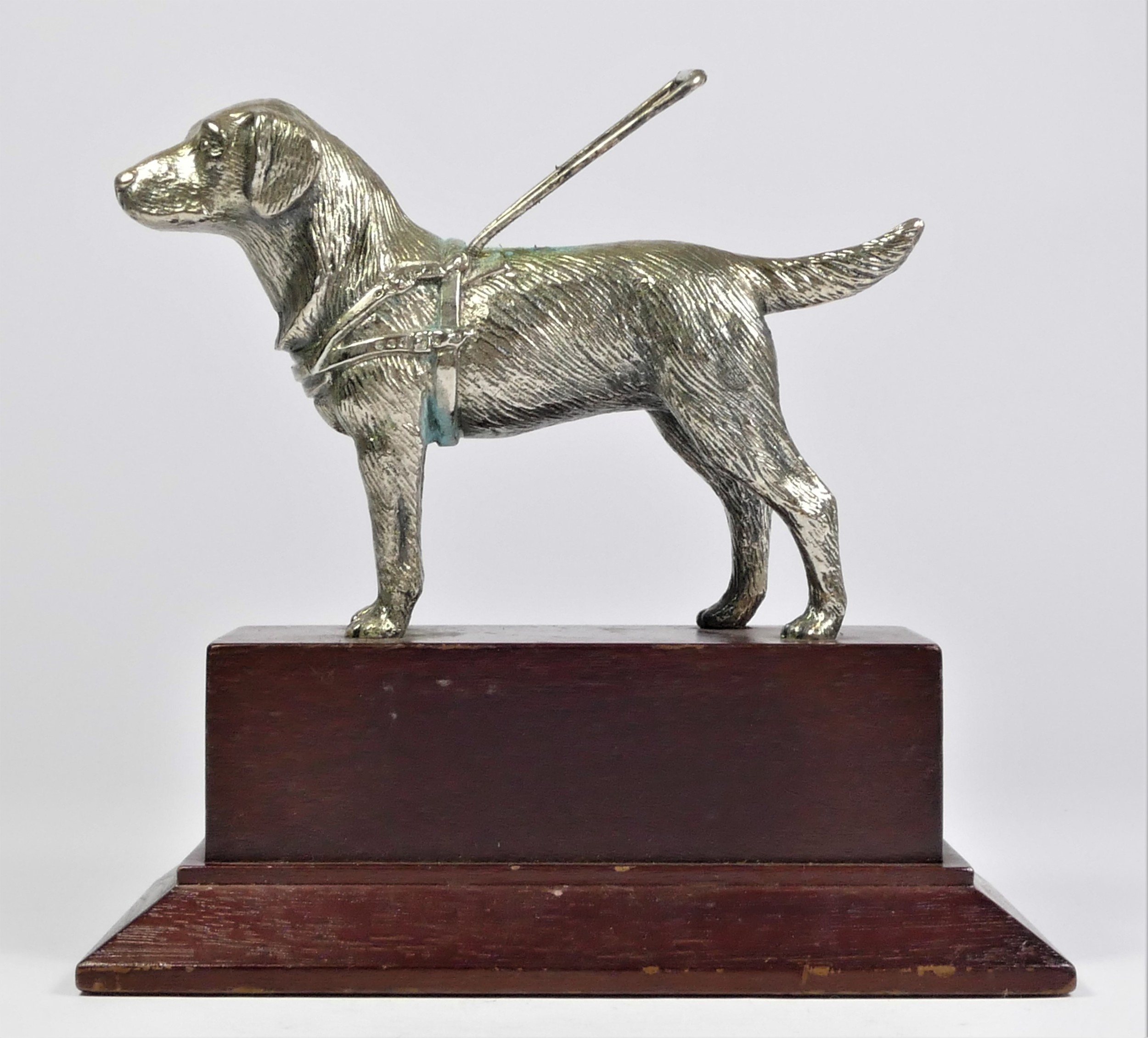 A chrome car mascot in the form of a Guide Dog, mounted on a wooden base, 15cm.