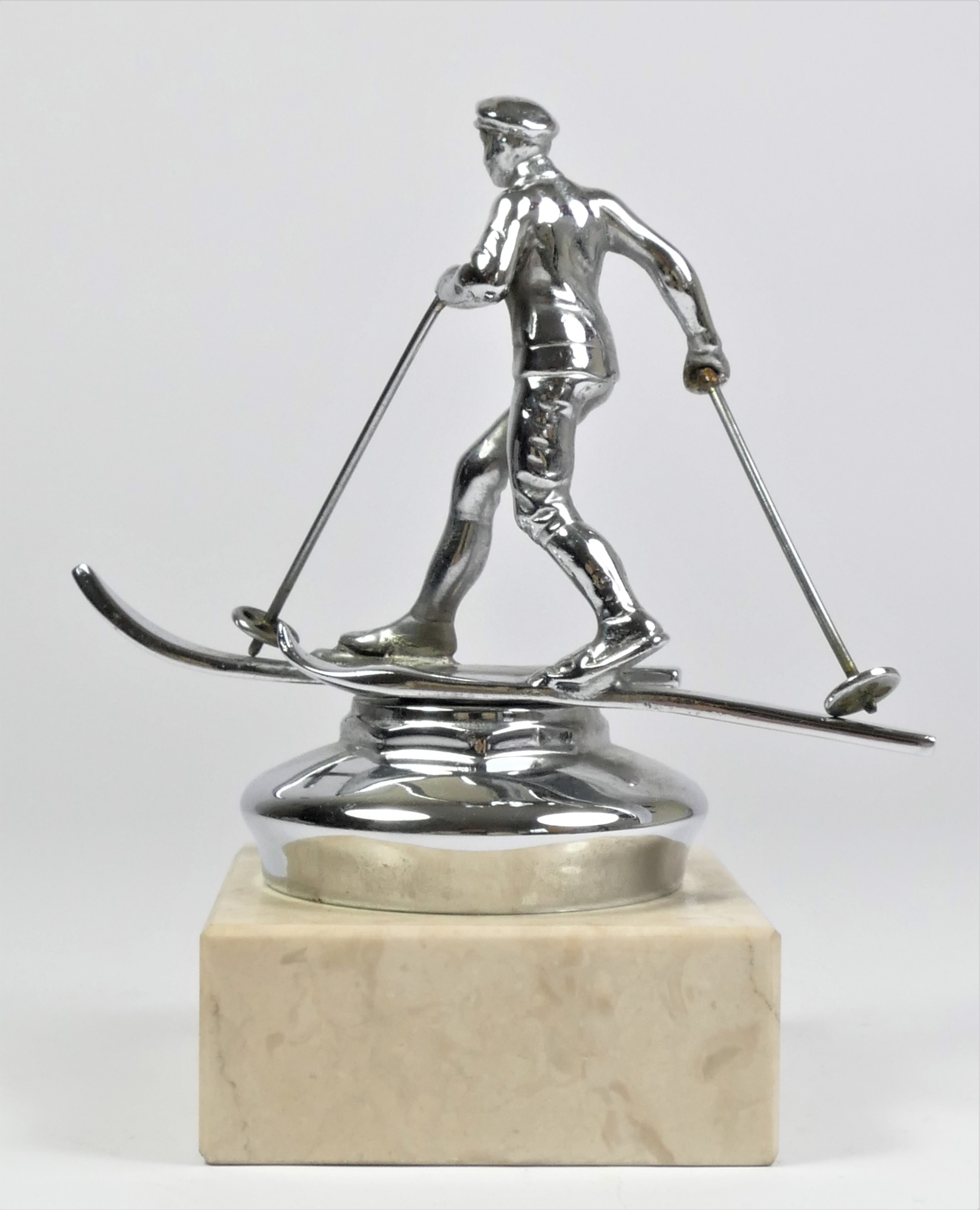 A chrome car mascot in the form of a skier mounted on a white onyx base, 15cm. - Image 2 of 2