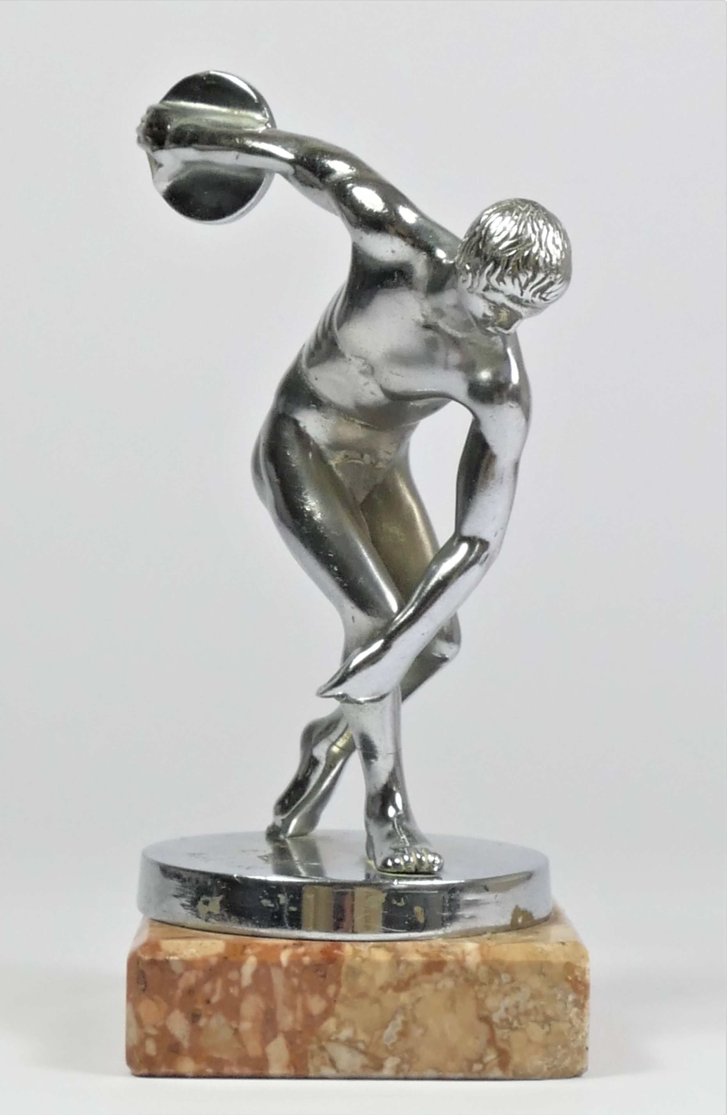 A chrome car mascot in the form of a discus thrower raised on a marble base, 16cm