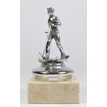 A chrome car mascot in the form of a skier mounted on a white onyx base, 15cm.