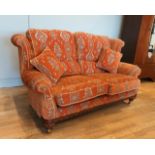 A Parker Knoll two seater sofa, upholstered in a baslow terracotta medallion gold fabric, raised