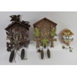 Two black forest cuckoo clocks together with a German made novelty wall clock in the form of a Swiss