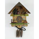 A novelty cuckoo clock, wooden case, depicting an articulated woman seated at a spindle, in a