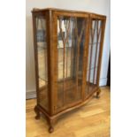 A mid 20th Century Turnidge display cabinet having two serpentine glazed doors opening to reveal two