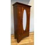 An Edwardian inlaid mahogany single wardrobe having central bevel edge oval mirrored door, inlaid