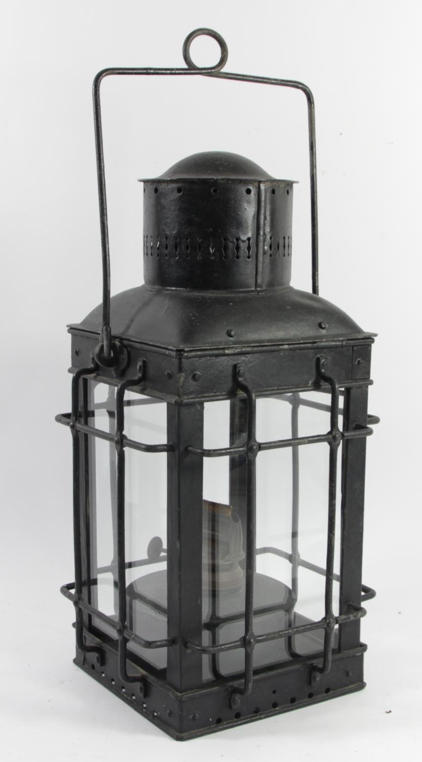 A hand lantern in protective metal cage with burner