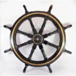 A large black painted and brass ships wheel, stamped AJAX, diameter 106cm.