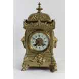 A late 19th century ornate cast brass mantel clock, off white enamel chapter ring with Roman