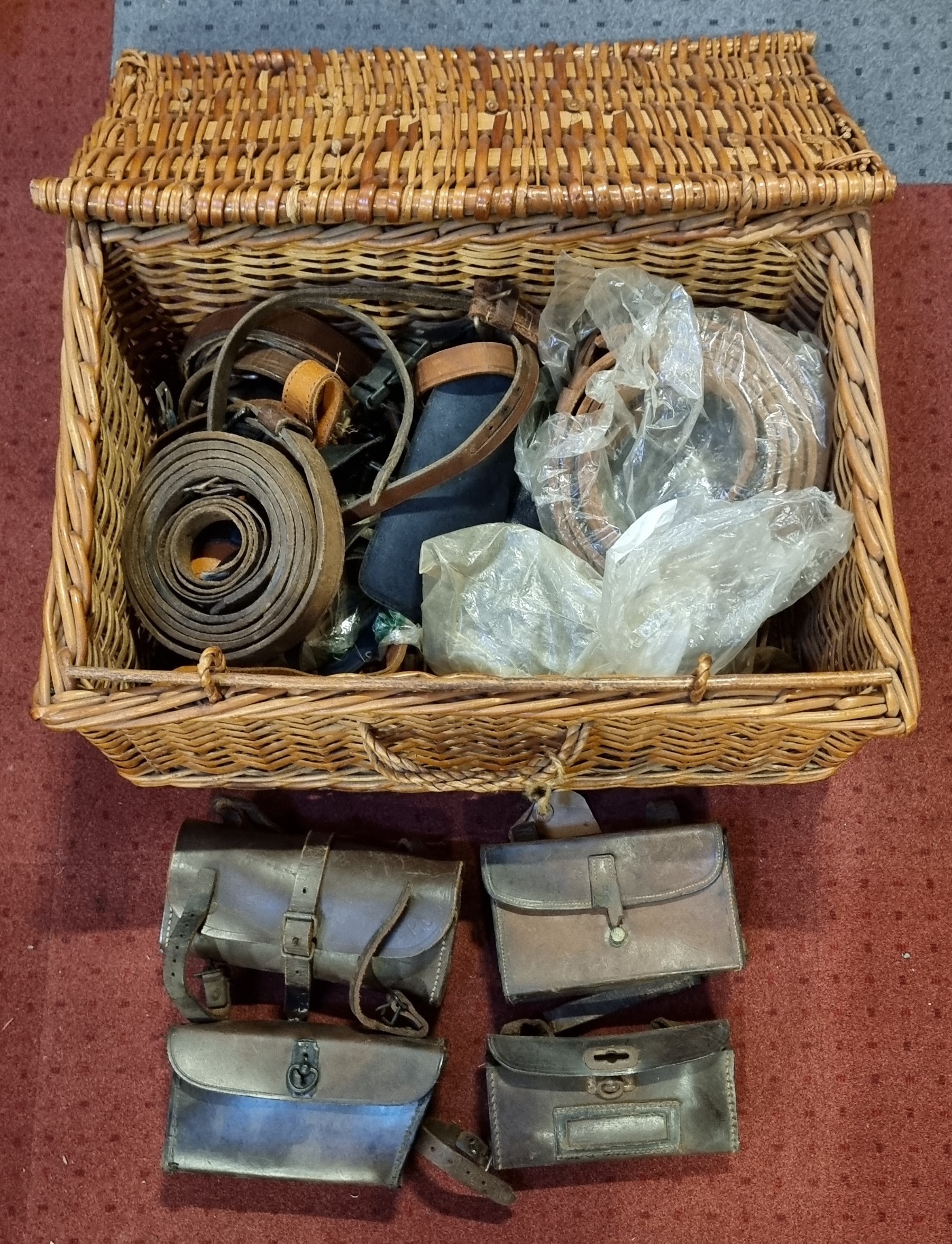 Four leather vintage tool bags, various leather belts and buckles, contained in a wicker basket