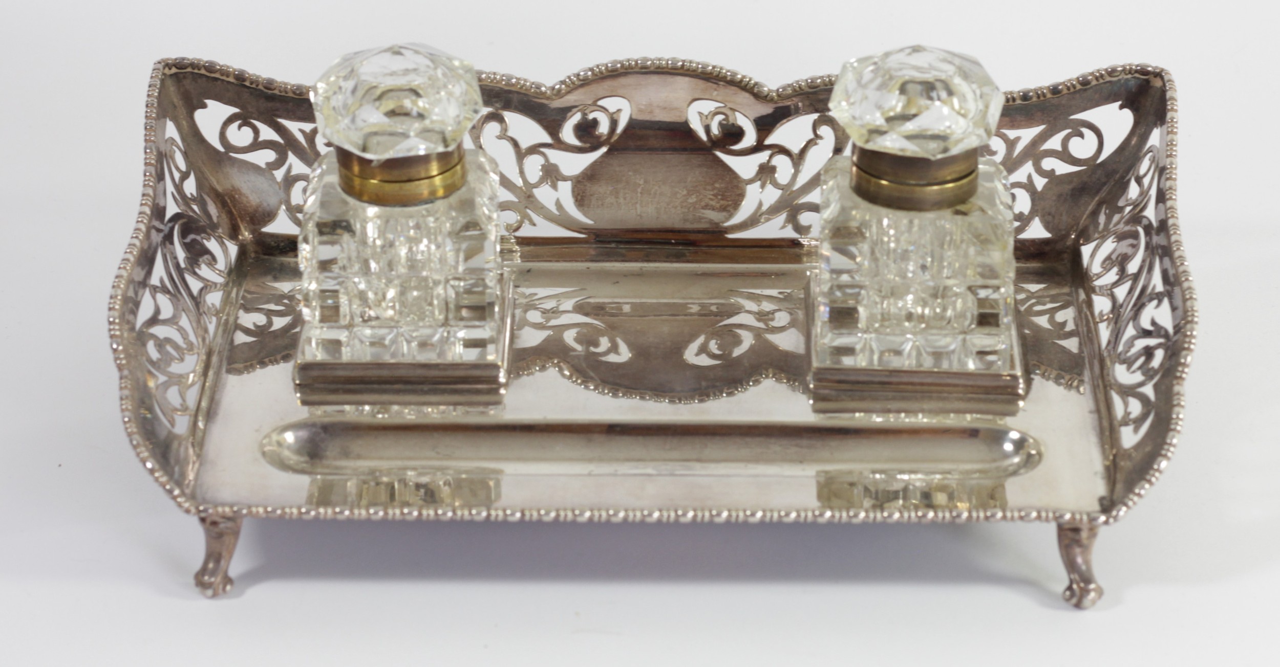 An electroplated two bottle desk stand, 3/4 pierced gallery with gadrooned border, cut glass brass