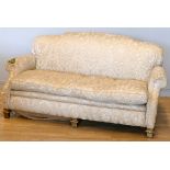 An early 20th century mahogany framed three seat sofa, with shaped back, sweep back and scroll arms,