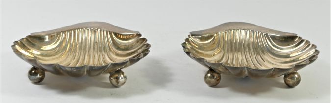 A pair of silver shell shape butter dishes, by Walker & Hall, London 1919, raised on three ball