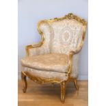 A Louis XV style mahogany framed wing back armchair, with carved giltwood frame, sprung upholstered,