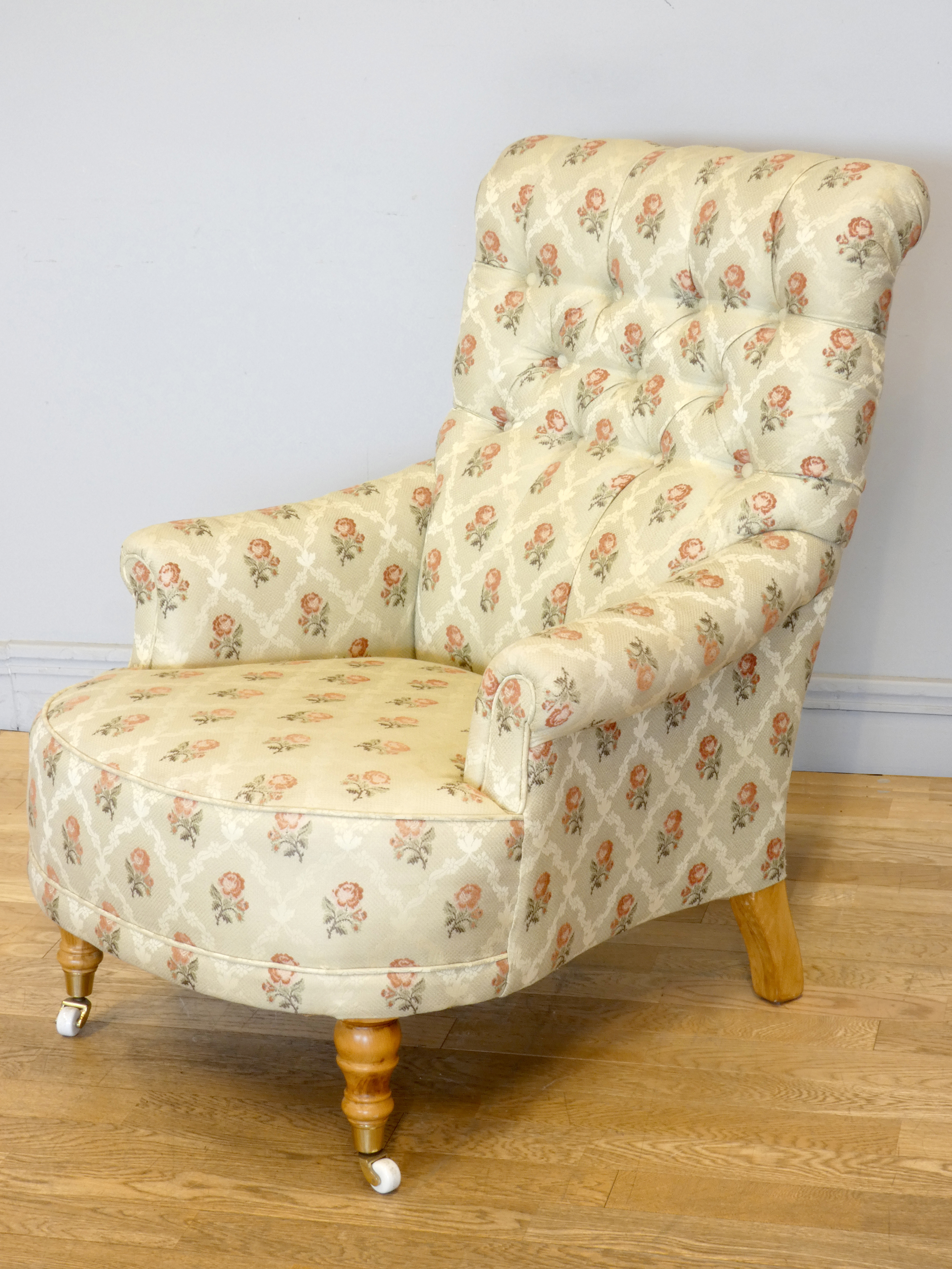 A Victorian style upholstered armchair, with button back and scroll arms, the front legs raised on