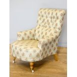 A Victorian style upholstered armchair, with button back and scroll arms, the front legs raised on