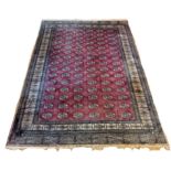 A Pakistani Peshawar Bokhara carpet, with red field and multiple guls, 360 x 290cm, A/F, 1989