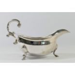 A silver gravy boat, London 1972, with wavy border and double scroll handle, raised on three shell