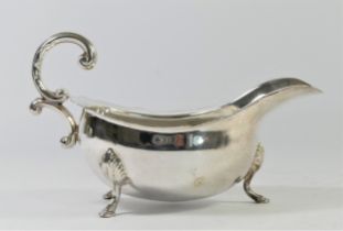 A silver gravy boat, London 1972, with wavy border and double scroll handle, raised on three shell