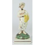 A pearlware figurine of Summer, c.1800-1820, modelled as a girl with sickle and sheath of corn, in