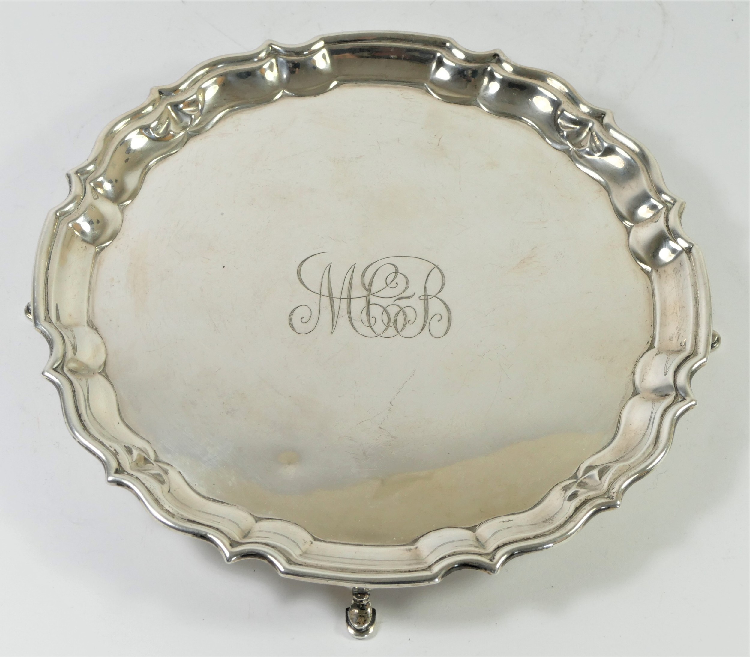 A silver waiter, by Barker Bros, Chester 1917, raised on four pad feet, monogrammed, 21cm, 358gm - Image 2 of 3