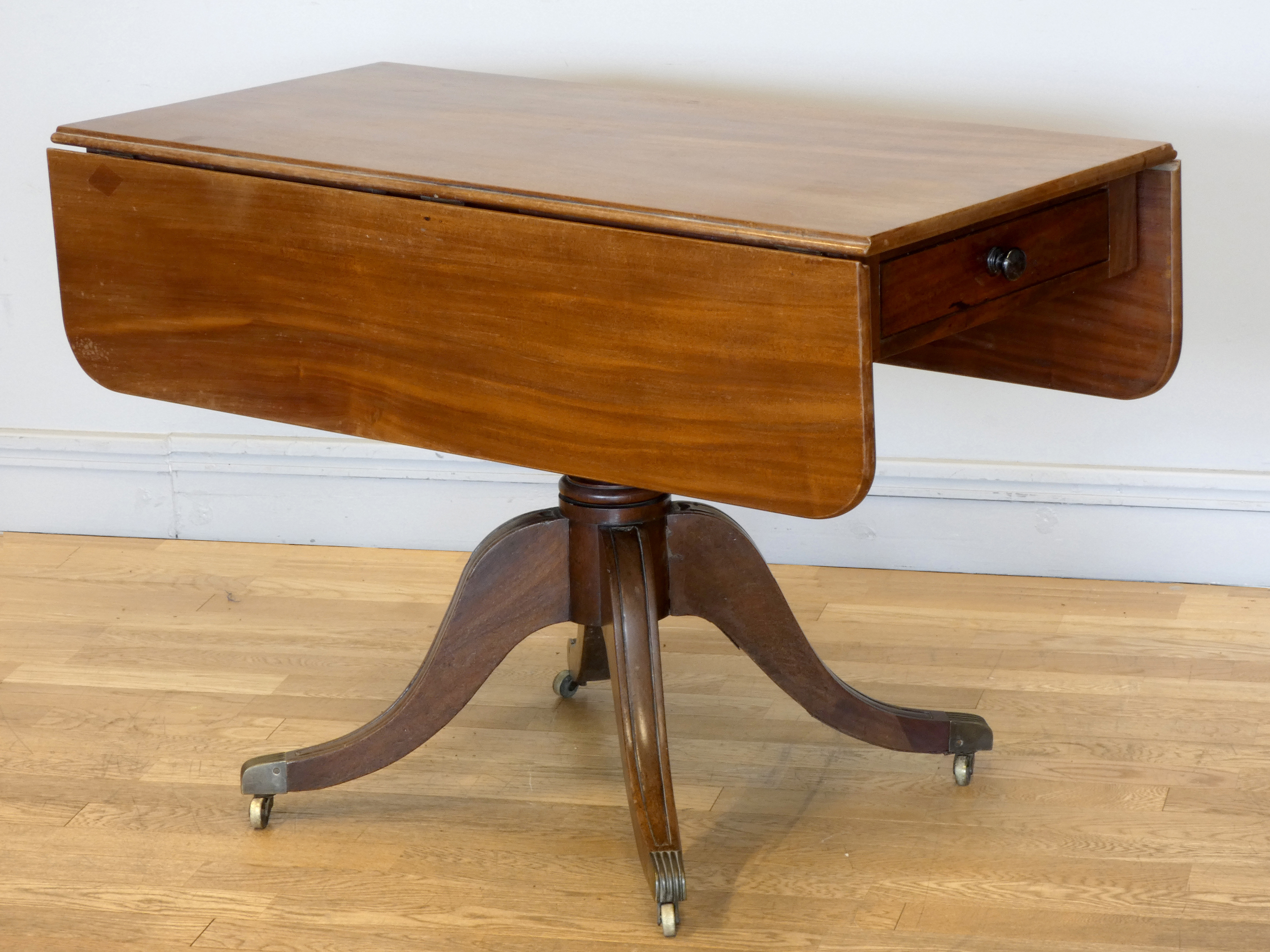 An early 19th century mahogany sofa table, raised on a turned pedestal, to a quatrefoil base, drawer